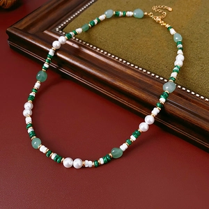 Detail of malachite and pearl necklace on a vintage frame showing elegant bead textures