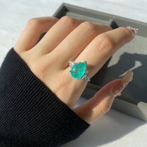 Macro shot of pear-cut paraiba gemstone ring with side diamonds on model's hand