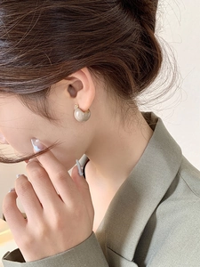 Detail of minimalist gold hoop earring with smooth grey marble resin ring on model