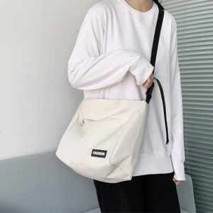 Detail view of large capacity cream canvas messenger bag with black FASHION label