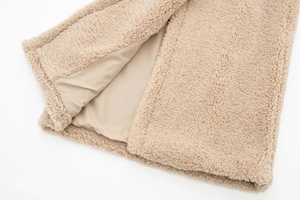 Detail of beige fleece coat showing textured faux wool surface and smooth inner lining