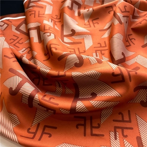 Gros plan d'un élégant foulard en soie orange avec imprimé monogramme et texture satinée