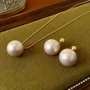 Detail shot of champagne pearl pendant necklace and earrings on green fabric