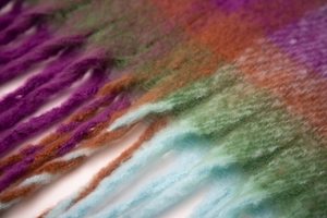Close-up of thick checkered boucle scarf with soft fringed edges and multi-color stripes