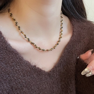 Dettaglio della collana occhio di tigre placcata oro 18k indossata da una modella con luce soffusa