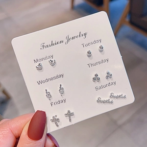 Close-up of 6 pairs of silver earrings on a weekly card set held by hand