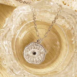 Irregular silver Turkish Evil Eye coin pendant necklace on ripple glass background