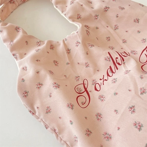 Nahaufnahme eines rosa Satin-Babylatzes mit roten Rosen und Sozakka-Schriftzug-Detail