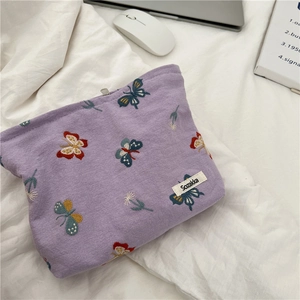 Detailed embroidery of colorful butterflies and flowers on purple linen cosmetic bag