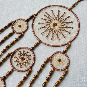Handcrafted brown and beige dreamcatcher with feathers and wooden beads on rings
