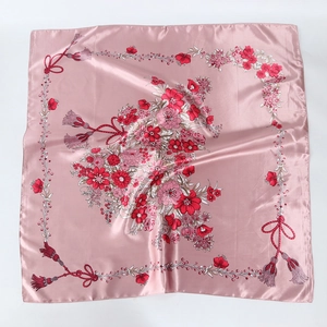 Détail du foulard carré en satin rose avec des imprimés floraux élégants et texture soyeuse