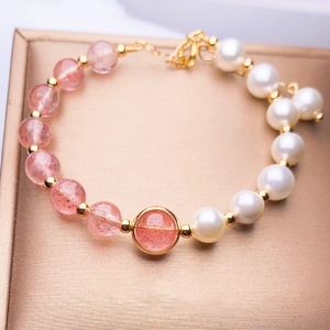 Detail of strawberry quartz beads and pearls with gold charms in a jewelry box