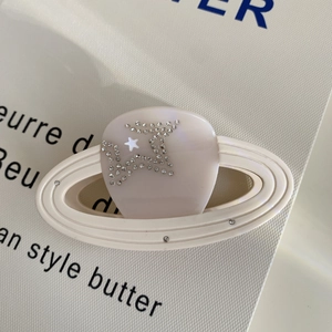Macro view of a white planet hair claw clip with crystal rhinestones and star design