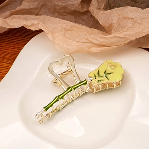 Detailed macro of bamboo-shaped gold hair claw clip with green enamel and pearls