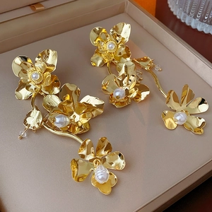 Detailed view of golden flower earrings with pearls resting in a professional jewelry box