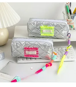 Detail of silver quilted stationery pouch with pleated trim and colorful lanyard handle