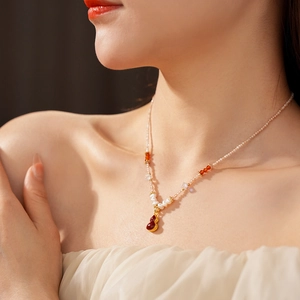 Detail of freshwater pearl necklace with crystal beads and red-brown gourd pendant on neck