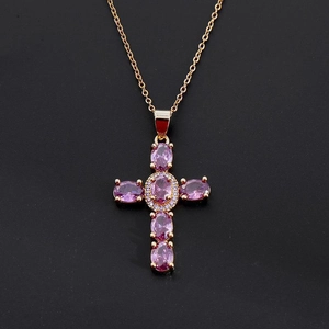 Detailed view of golden cross pendant featuring pink gems and brilliant zircon accents