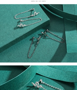 Macro shot of S925 silver snake tassel earrings with emerald and pink eyes details