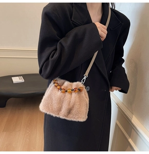 Model wearing a plush faux fur bucket bag in light coffee with beaded handle