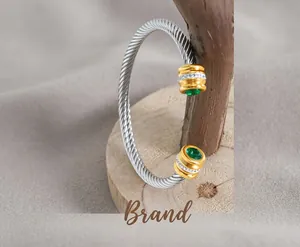 Detail of twisted cable steel bracelet with gold accents and green zircon inlay