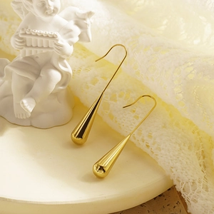 Elegant polished gold teardrop hook earrings displayed on a minimalist tray