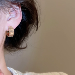 Close-up of elegant gold square hoop earring with rectangular cubic zirconia on ear