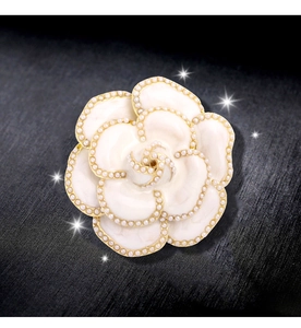 Détails d'une broche camélia avec pétales blancs, perles et bordures dorées