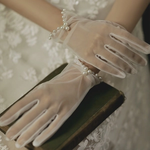 Detail showing white sheer mesh gloves with pearl bead wrist decoration on book