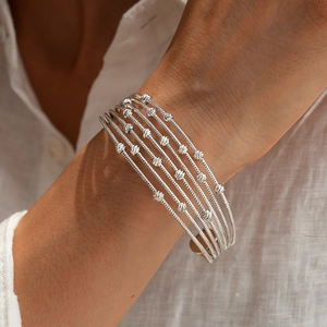 Detail of silver multi-layer open cuff bracelet with engraved metal beads and spiral texture