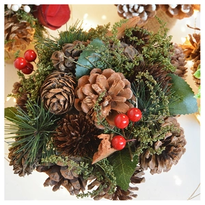Close-up of golden pine cones and red berries on festive evergreen branches decor