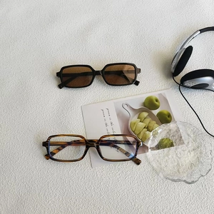Retro rectangular sunglasses in black and tortoiseshell finish on a minimalist desktop