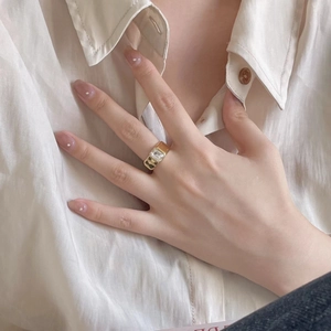 Close-up of elegant gold wide band ring with a rectangular clear zircon on finger