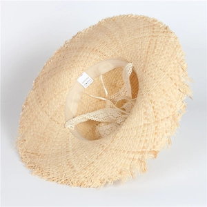 Detail of handmade raffia straw hat showing the inner white lace and fabric care label