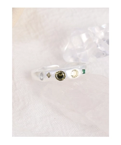 Macro shot of silver S925 ring with five multicolored zircon stones on white fabric