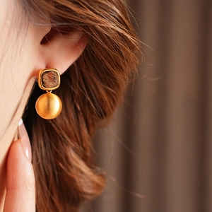 Close-up of elegant gold geometric drop earrings worn by a model in warm lighting