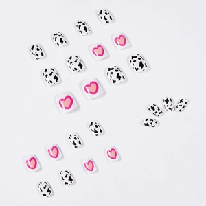 Cow print and pink heart patterns on short square false nails set in a flat lay view