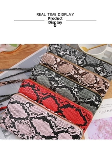 Collection of faux snakeskin long wallets in various colors with wrist straps on a desk