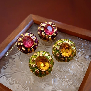 Detail of vintage oval earrings with purple and green enamel and crystal stones