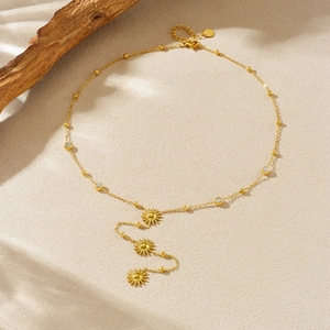 Golden sun pendant necklace with zircon accents on natural beige background