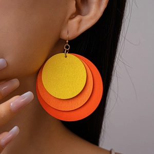 Detail of multi-layered round wooden drop earrings with yellow to orange gradient finish