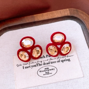 Macro shot of oval champagne crystal stud earrings on red velvet base with retro style