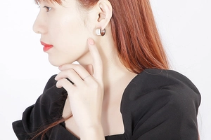 Close-up of stylish shell-patterned earrings and a minimalist ring on a female model