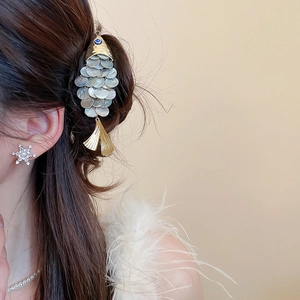 Close-up of golden fish hair clip with iridescent shell scales worn on side profile