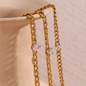 Detail of 18K gold plated chain bracelets with marquise and round cubic zirconia on a vase