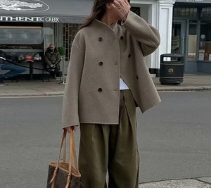 Detail view of camel double-breasted wool coat with stand collar and wide sleeves