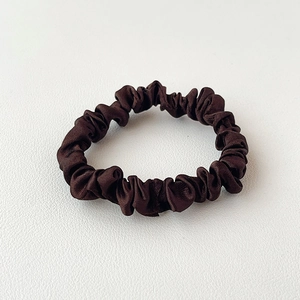 Macro detail van de gladde donkerbruine satijnen scrunchie op witte achtergrond