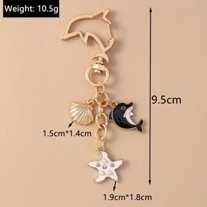 Detail of dolphin keychain with gold shell and starfish charms, weighing 10.5g