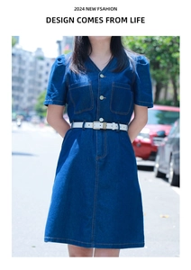 Detail of V-neck denim dress featuring a white leather belt and functional front pockets