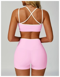 Detail of pink sports bra with white contrast straps and crisscross open back design